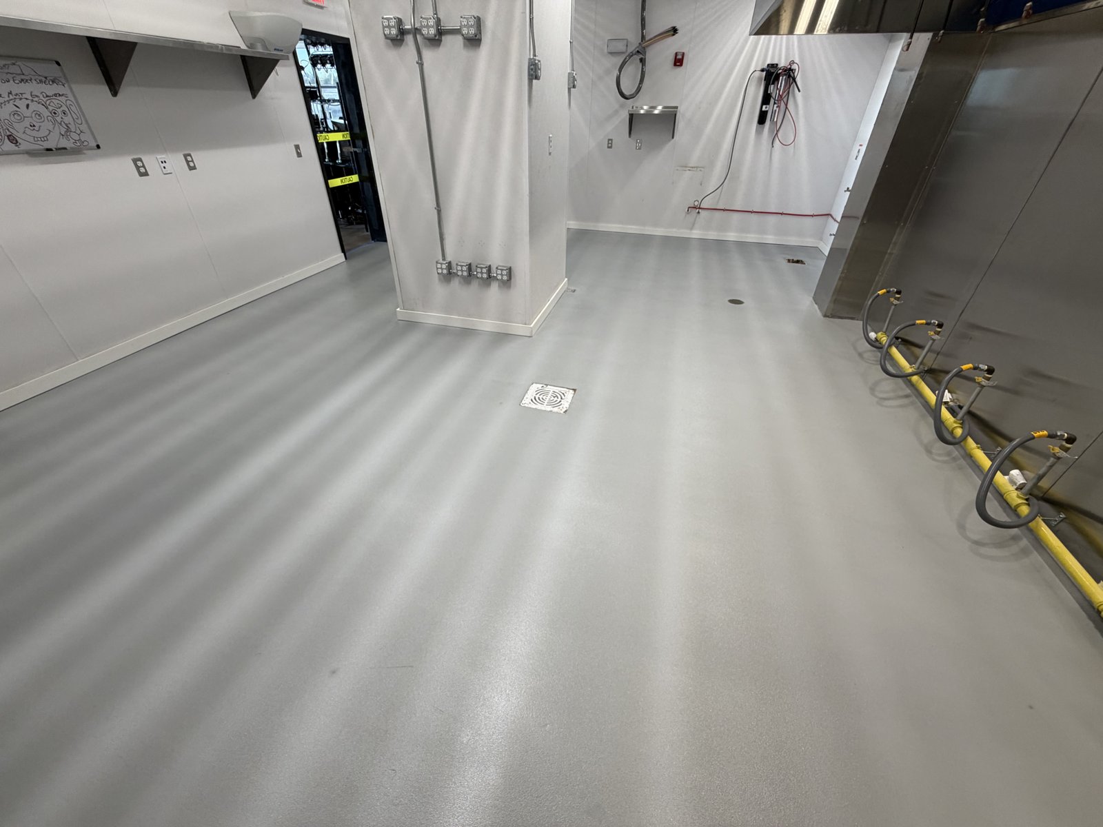 Commercial kitchen with chemical-resistant coating and floor drain, comparable to school cafeteria kitchen flooring