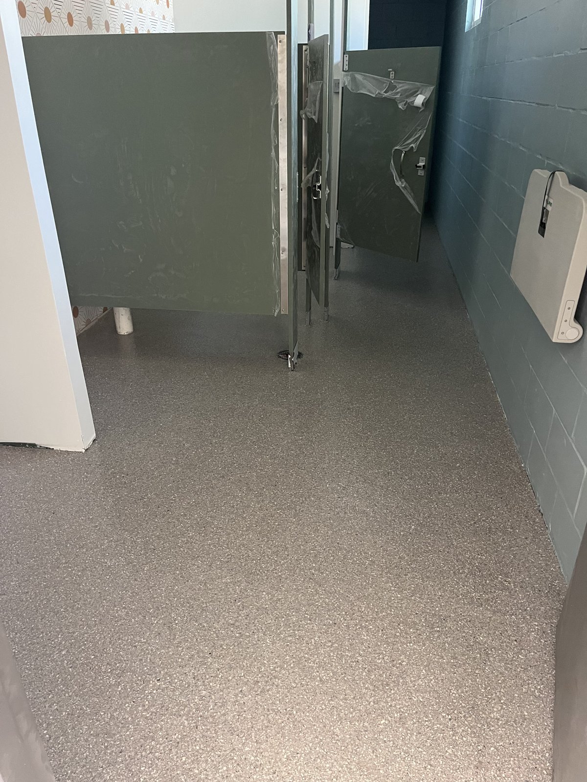 Commercial restroom with gray decorative flake floor, ideal for school locker room and bathroom coatings