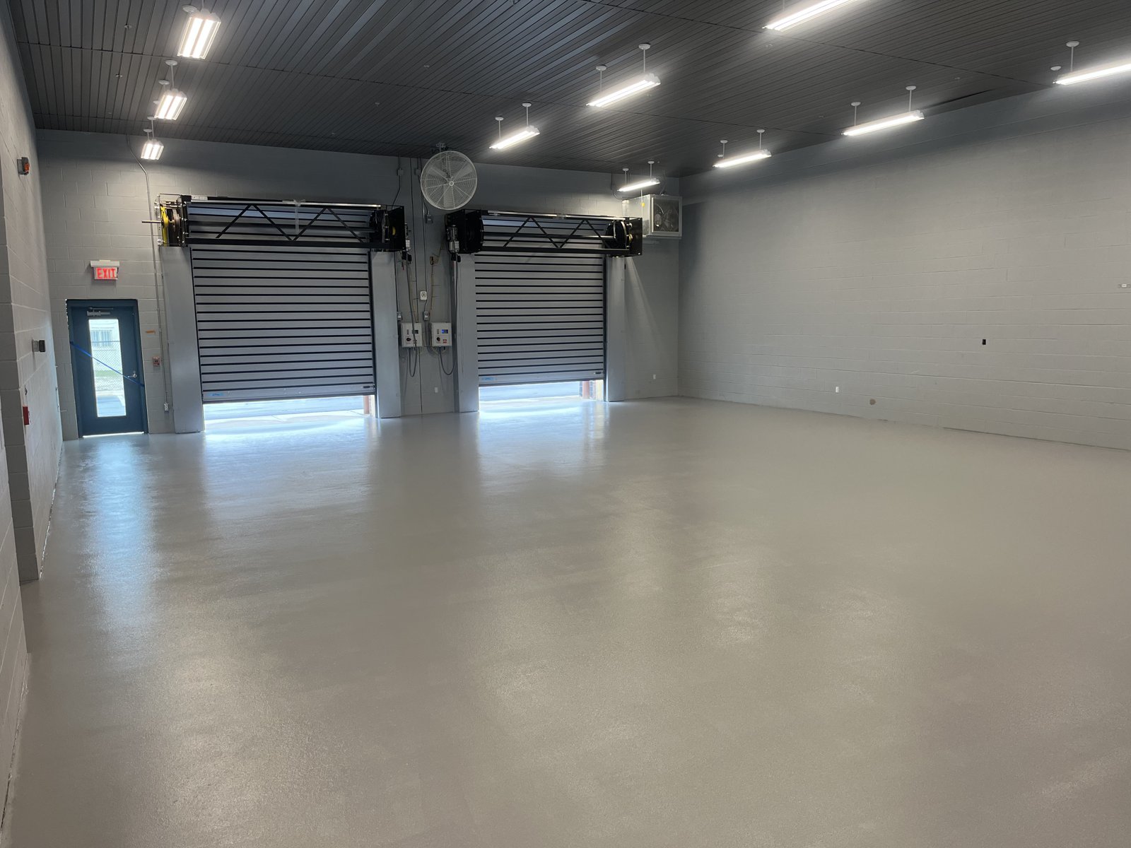 Service bay with gray polyaspartic coating and roll-up doors
